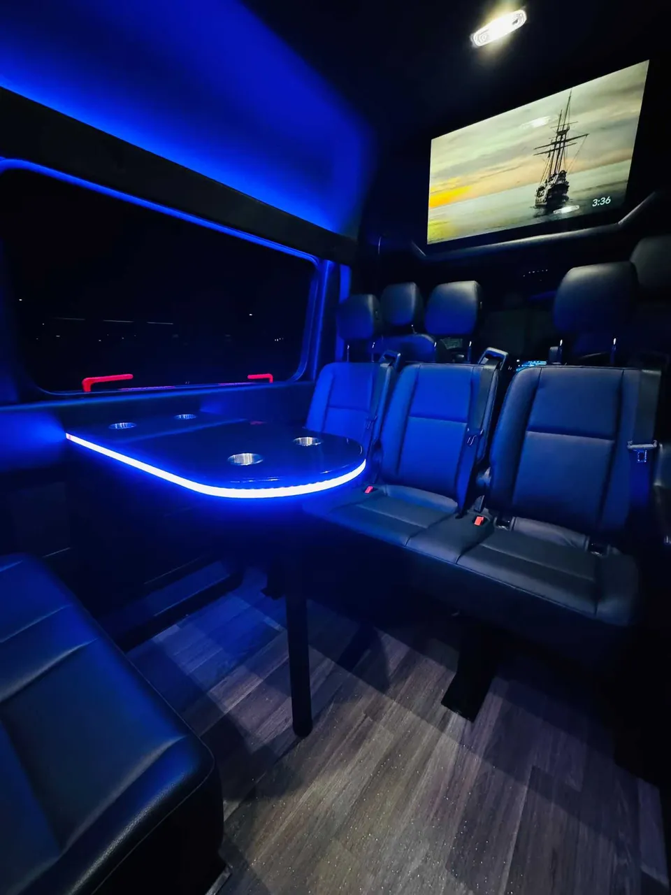 Mercedes-Benz Executive Sprinter for party bus rental: seating area, with passenger tables, LED accent lighting and wood-look flooring, pic 2