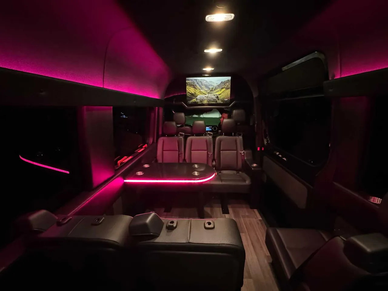 Mercedes-Benz Executive Sprinter for party bus rental: seating area, with passenger tables, LED accent lighting and wood-look flooring