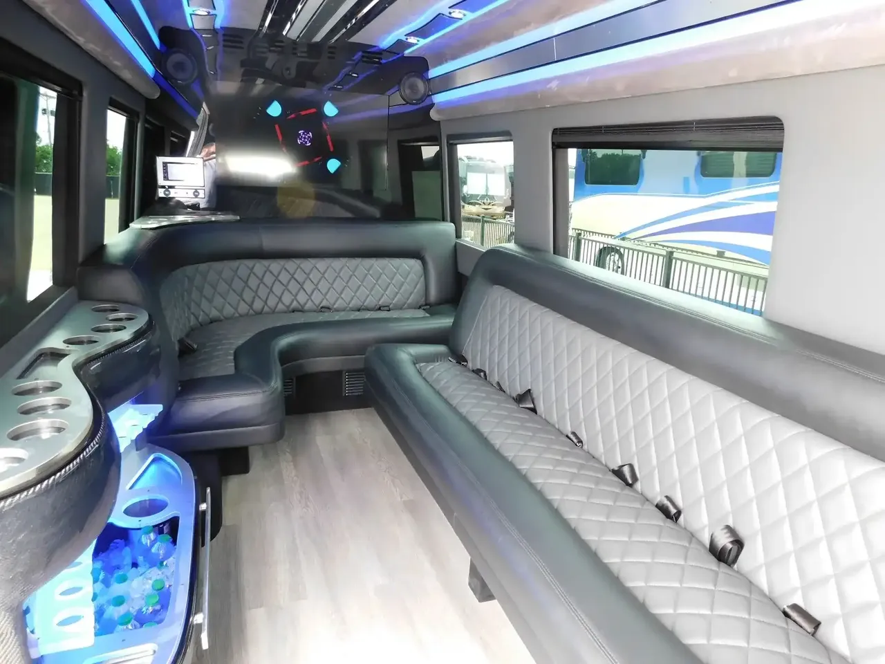 Mercedes-Benz Sprinter Limousine for party bus rental: seating area, with perimeter lounge seating, LED accent lighting and wood-look flooring