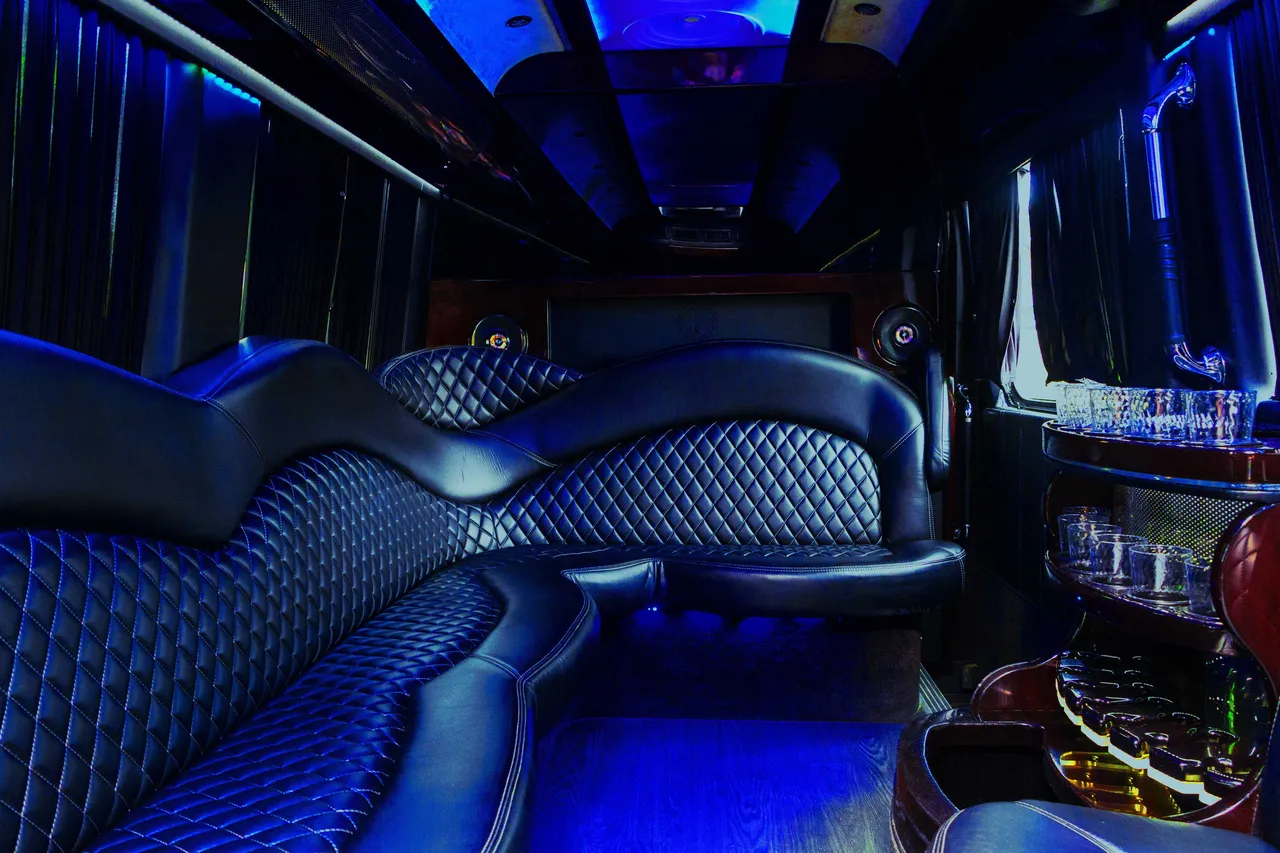 Mercedes-Benz Sprinter Limousine for party bus rental: seating area, with sofa-style seating, window shades and bar area