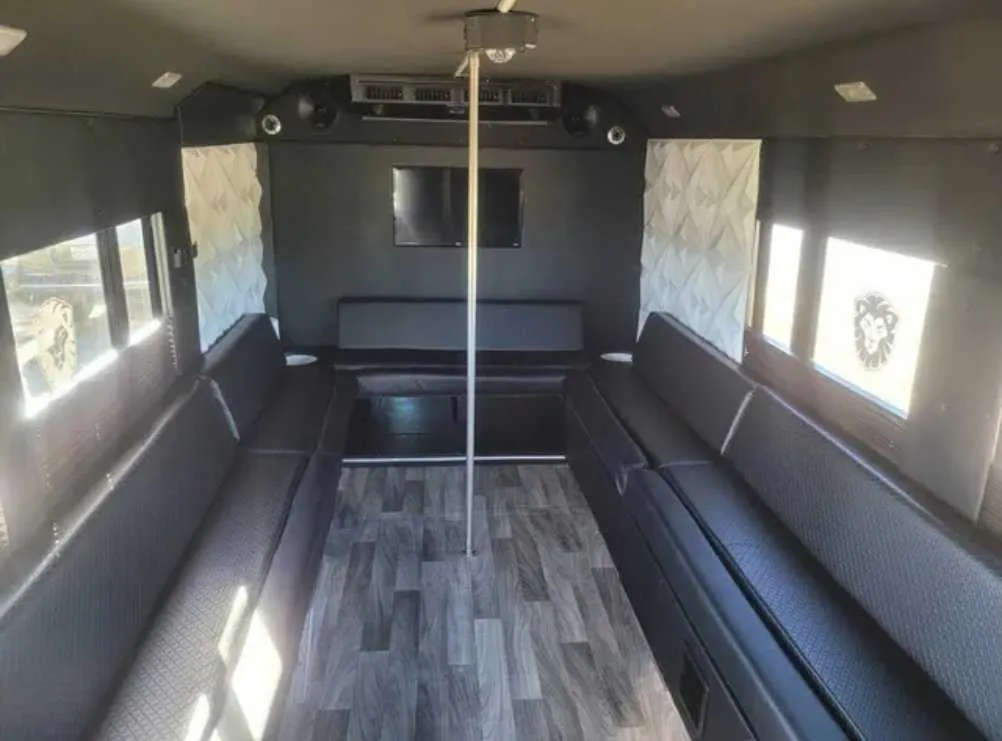 Tuxedo Party Bus Tuxedo Party Bus: seating area, with perimeter lounge seating, wood-look flooring and TV screens